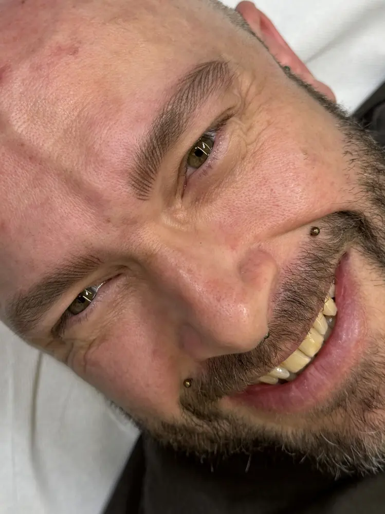 Cliente uomo sorridente dopo il trucco permanente alle sopracciglia